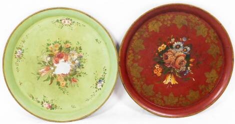 Two early 20thC Toleware style tin plates, each of circular form, hand painted with flowers, with a gilt stenciled floral outline, 45cm diameter.