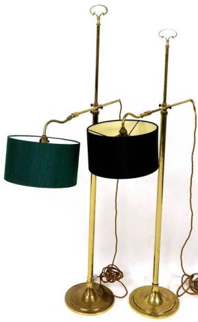 A pair of 20thC brass lamp standards, with adjustable arms and circular bases, each surmounted by shaped scroll handles, 132cm high, with various shades.