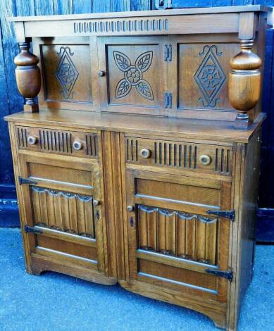 A 20thC oak court cupboard, of rectangular form, the upper section with heavy baluster supports, centred by a cupboard above two frieze drawers and double cupboard beneath, on block stiles, 142cm high, 121cm wide, 49cm deep.