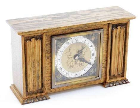 A Hoppers Elliot and Co oak cased mantel clock, of rectangular form, the 9cm diameter dial, with 8cm chapetering, the 9cm back plate with raised spandrels, Roman numeric dial, flanked by linen fold panels on compressed carved feet, with Elliot movement 14