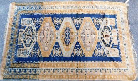 A 20thC Iranian woollen rug, of rectangular form, decorated with a floral and geometric pattern, predominantly in blue and yellow, 207cm x 131cm.