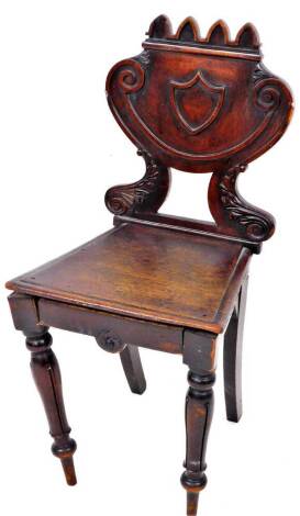 A 19thC mahogany hall chair, with castellated top, above a raised shield and scroll splat, on scroll supports, with a deep seat, on turned reeded front and saber back legs, 88cm high.