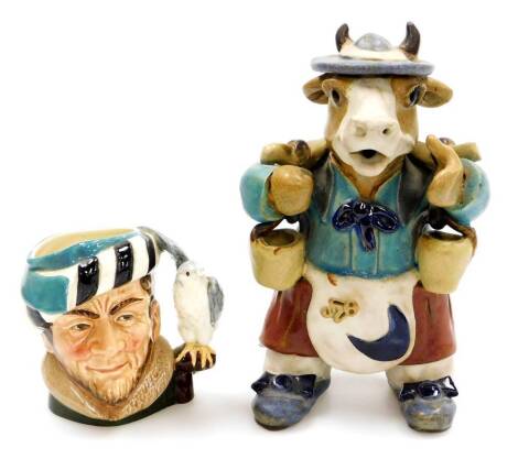 An unusual Continental pottery standing cow figure, wearing apron, boots and hat, polychrome decorated predominantly in blue, turquoise and orange, 21cm high, and a Royal Doulton small character jug with a Falconer D6540, printed marks beneath. (2)