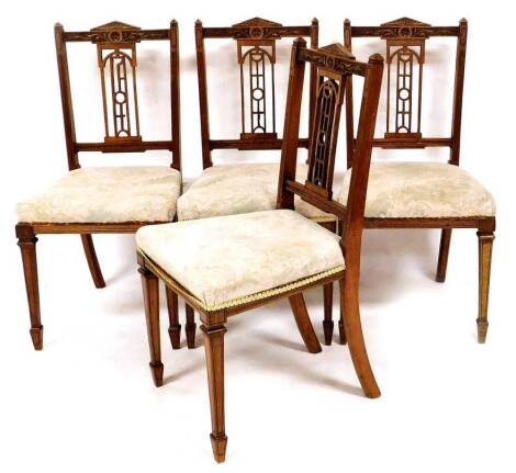 A set of four Edwardian dining chairs, each with pierced back splats, overstuffed seats in later floral material, on square tapering legs terminating in spade feet, 89cm high.