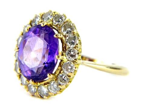 An amethyst and diamond dress ring, with oval cut amethyst 8.9mm x 10.4mm x 4.8mm, in an eight claw setting surrounded by sixteen round brilliant cut diamonds each approx 0.15cts, on a plain polished yellow metal band, unmarked, ring size N½, 5g all in, b