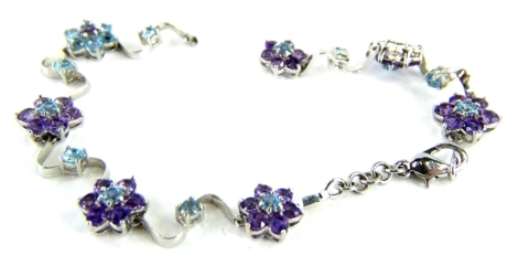 A stone set floral bracelet, with design of floral clusters each set with amethyst and aquamarine coloured stones, with twist wave links, white metal in colour, unmarked, 20cm long overall. (AF)