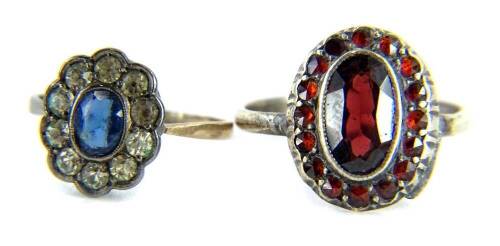 Two dress rings, comprising a silver and red paste stone set dress ring, and a 9ct gold cluster ring, set with oval blue stone, surrounded by white stones, ring size J. (2)