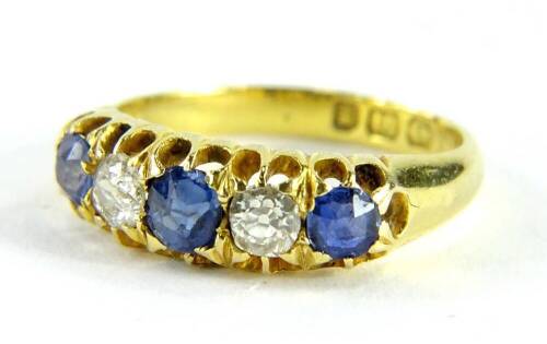 An 18ct gold sapphire and diamond gypsy ring, set with three cornflour blue sapphires and two diamonds, each in a claw setting, on a plain band, ring size I½, 3.1g all in.