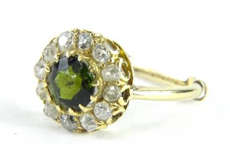 A peridot and diamond ring, set with central round brilliant cut stone in claw setting, surrounded by old cut diamonds, in a raised circular setting, yellow metal, unmarked, with a 9ct gold ring sizer insert, ring size L, 3g all in.