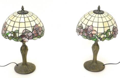 A pair of Tiffany style table lamps, each with a stained glass shade, decorated with purple flowers, etc., gilt base, 48cm high.