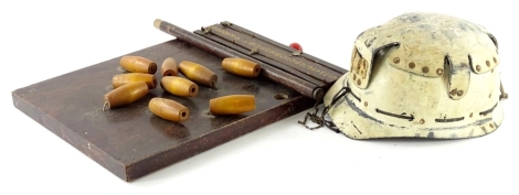 A vintage miners helmet, painted in cream, possibly the Huwood light type hat, indistinct label to underside and a bar skittles game (2)