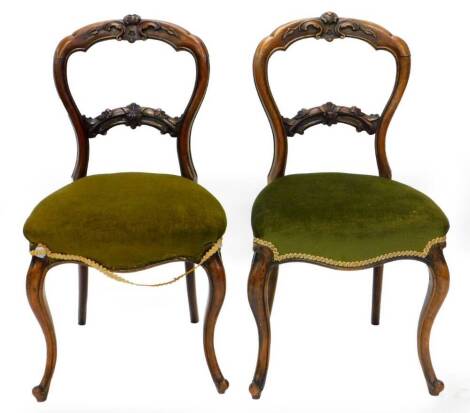 A pair of Victorian rosewood balloon back chairs, each with a padded seat on cabriole legs.