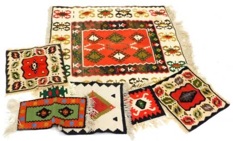 A modern Kilim rug, with a geometric design on a red ground with cream and brown borders, and various smaller Kilim mats.