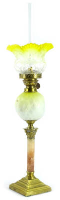 A Victorian brass oil lamp, with a small yellow and white frosted shade, brass fitting, the yellow and white opaque satin glass reservoir in the manner of Thomas Webb, on a pink alabaster and brass Corinthian column base, (AF), 56cm high overall.