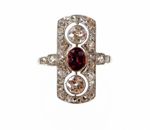 A Victorian ruby and diamond panel ring, the panel set with two old cut diamonds, each 4.2mm x 4.2mm x 2.2mm, approx 0.27cts each, each in platinum rub over setting, with a central oval cut ruby, 5.2mm x 4.2mm x 3.8mm, approx 0.66cts, in a yellow rub ove