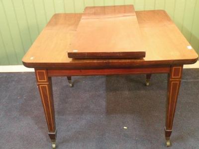 An Edwardian mahogany extending dining table on square tapering