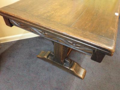 An oak draw leaf dining table with a carved frieze on canted