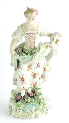 A late 18thC Derby porcelain lady, modelled holding flowers in her dress, on a flower encrusted rococo scroll base, (AF), 25cm high.