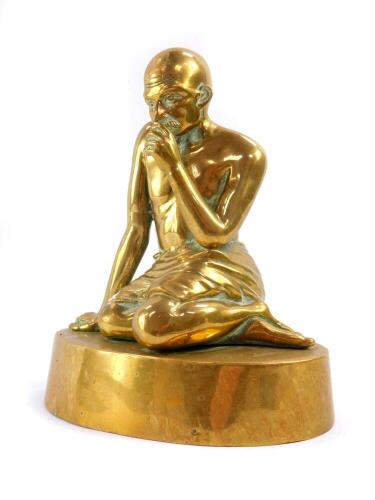 A brass figure of Mahatma Gandhi, modelled kneeling on an oval base, 20cm high.