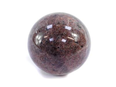 A Mozambique veined and dappled granite ball, shades of purple and grey, 10cm diameter.