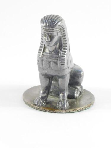 An Armstong Siddeley early 20thC aluminium coated brass car mascot, modelled as a seated sphynx, on a circular base, 9cm high.