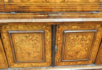 A 18thC Dutch marquetry corner cabinet, with fixed swan neck pediment, raised above heavily carved shelves and cupboard beneath, profusely decorated with leaves and flowers with a lower geometric inlay, fronted by two elaborate designed doors, 243cm high, - 2