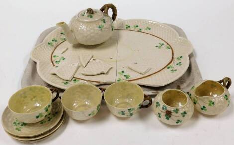 An early 20thC Belleek part tea service, decorated with clover, comprising teapot with bark handle 10cm high, three cups, three saucers, milk jug and sugar bowl on a shaped tray, black dog harp and Fermanagh marked beneath. (10, AF)