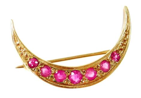 A 9ct gold garnet set crescent brooch, the crescent moon set with seven graduated stones, on a single pin back, 2.5cm wide, 2.8g all in.