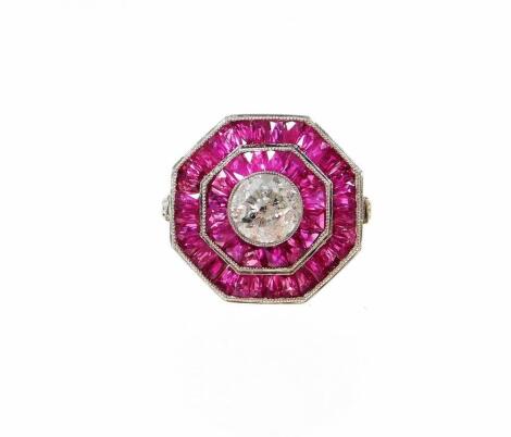 An octagonal ruby and diamond ring, with central round brilliant cut diamond, in rub over setting, 5.8mm x 5.8mm x 4mm, approx 1ct, with baguette and calibre cut rubies, in two outer layers, totalling approx 2.75cts, with diamond set shoulders, in open wo