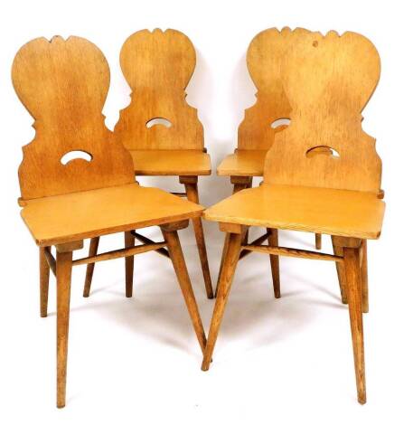 A set of four 20thC carved oak chairs, each with shield backs and pierced handles to the splats, with plain seats on turned legs, 96cm high.