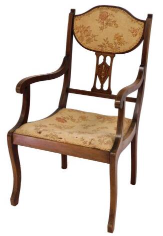 An Edwardian mahogany salon carver chair, with overstuffed back and seat, in floral material, and an inverted pierced back splat centred by an inlaid shield, on sabre front legs, partially boxwood strung, 96cm high.