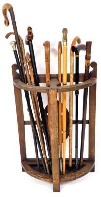 An early 20thC demi lune stick stand, with lead liner and a quantity of walking sticks, to include Shepherd's crook, later walking stick with duck handle 90cm high, another with brass horse head, various other walking sticks, etc. (a quantity)