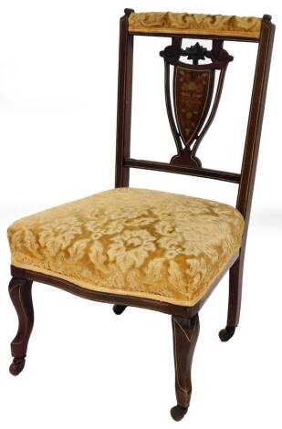 An Edwardian bedroom chair, with shield marquetry inlaid back, on gold upholstered seat, in shaped legs on castors.