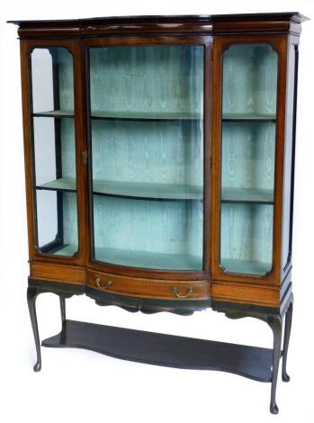 An Edwardian mahogany and checker banded display cabinet, with a shaped top, a bow fronted central glass door flanked by glazed sides, above a frieze drawer, with a shaped apron on cabriole legs and pad feet, 173cm high, 232cm wide.