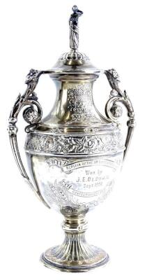 A small two handled silver urn shaped trophy and cover, decorated with flowers, leaves, etc., the lid decorated with a lady finial, engraved to one side Replica of the 80 Guinea National Confectionary Cup, Won by J.E. Oldham Sept 1902, Sheffield 1902, mad