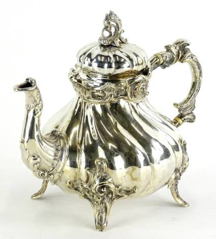 A continental white metal teapot, of rococo form with a pierced knop, scroll cast bands and a wrythen body, the 'C' scroll handle with ivory insulators, stamped to underside 800, and with a double sided eagle crest, possibly German, 21¾ oz.