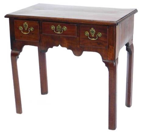 A George III mahogany lowboy, the rectangular top with a moulded edge, above three frieze drawers and a shaped apron, on chamfered legs, 70cm high, 76cm wide, 46cm deep.