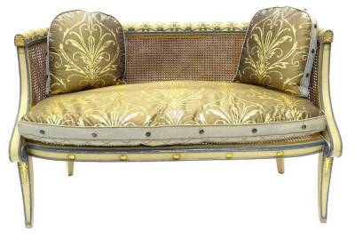 A Regency bergere sofa, painted in cream and powder blue, the frame carved with acanthus, fans and scrolls, with a caned back and seat, fitted gold, blue and black fabric seat cushion with other matching cushions, on sabre legs, 132cm wide.