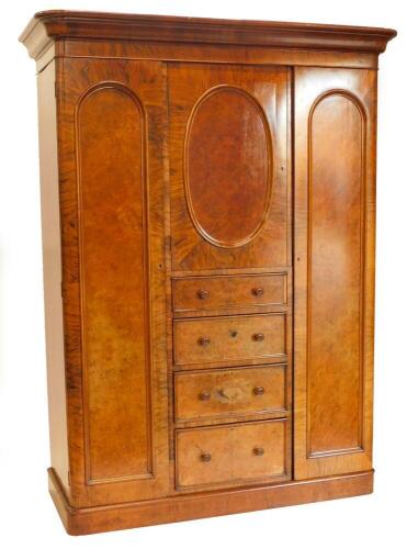 A Victorian walnut and burr walnut triple wardrobe, of small proportions, the top with a moulded cornice above a door with an oval panel, and four drawers each with turned wood handles, flanked by two full length doors, each with arched panels enclosing a