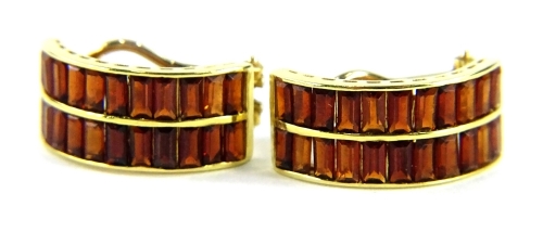 A pair of 18ct gold garnet set half hoop earrings, each set with two rows of baguette cut garnets, in a yellow metal frame, with single pin and clip back, 2cm high, 7.6g all in.