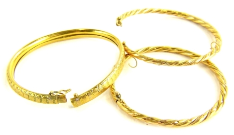 Three bangles, two yellow metal rope twist bangles, with safety clasps, and another with hammered design, marked 916, 34.1g all in.