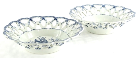 A pair of 19thC Worcester type porcelain baskets, each printed in blue with pine cones, flowers, etc., within pierced borders, crescent mark to underside, (AF), 26cm diameter.