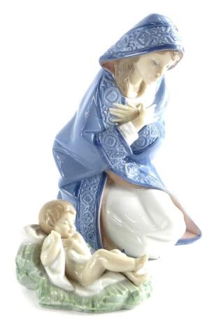 A Lladro porcelain figure of a kneeling lady wearing a cloak, impressed number 2477, 17cm high, and a Lladro porcelain model of a young baby reclining on rushes, possibly Moses, 10cm long, (2).