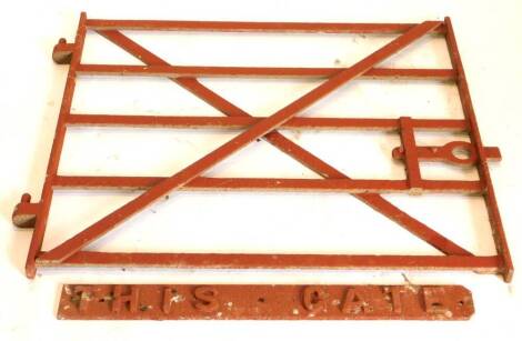 An iron red painted wrought iron five bar gate, with cross stretcher, 83cm high, 94cm wide, and a sign 'This Gate', 76cm wide.