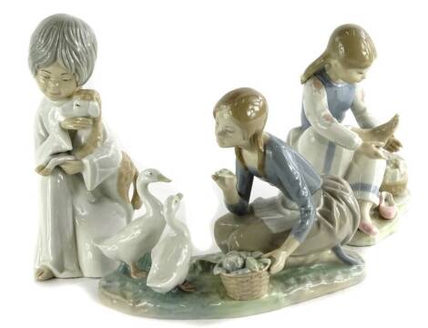 A Lladro porcelain figure of a young girl with two geese, similar Nao figure of a lady seated wearing pink shoes and a Spanish porcelain figure of a young girl with a goat (AF).