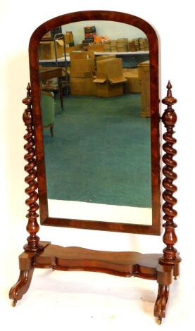 A Victorian figured mahogany cheval mirror, with an arched plate, spirally turned supports and platform base with scroll carved feet and brass castors, 96cm wide.