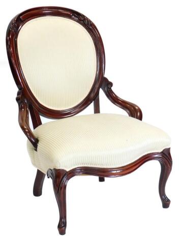 A Victorian mahogany showframed nursing chair, with a padded back and seat upholstered in gold stripped fabric, on cabriole legs.