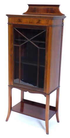 An Edwardian mahogany and satinwood cross banded display cabinet, with a raised back above a single astragal glazed door, on splayed legs with undertier, 152cm high, 61cm wide.