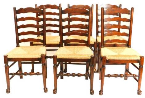 A set of six oak ladder back chairs, each with a rush seat on turned tapering legs.