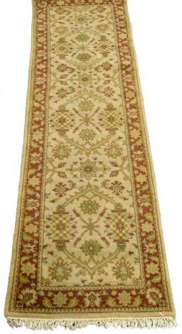 An Afghan runner, with a design of flowers, leaves, etc., on a dark beige ground with one wide border, 242cm x 74cm.